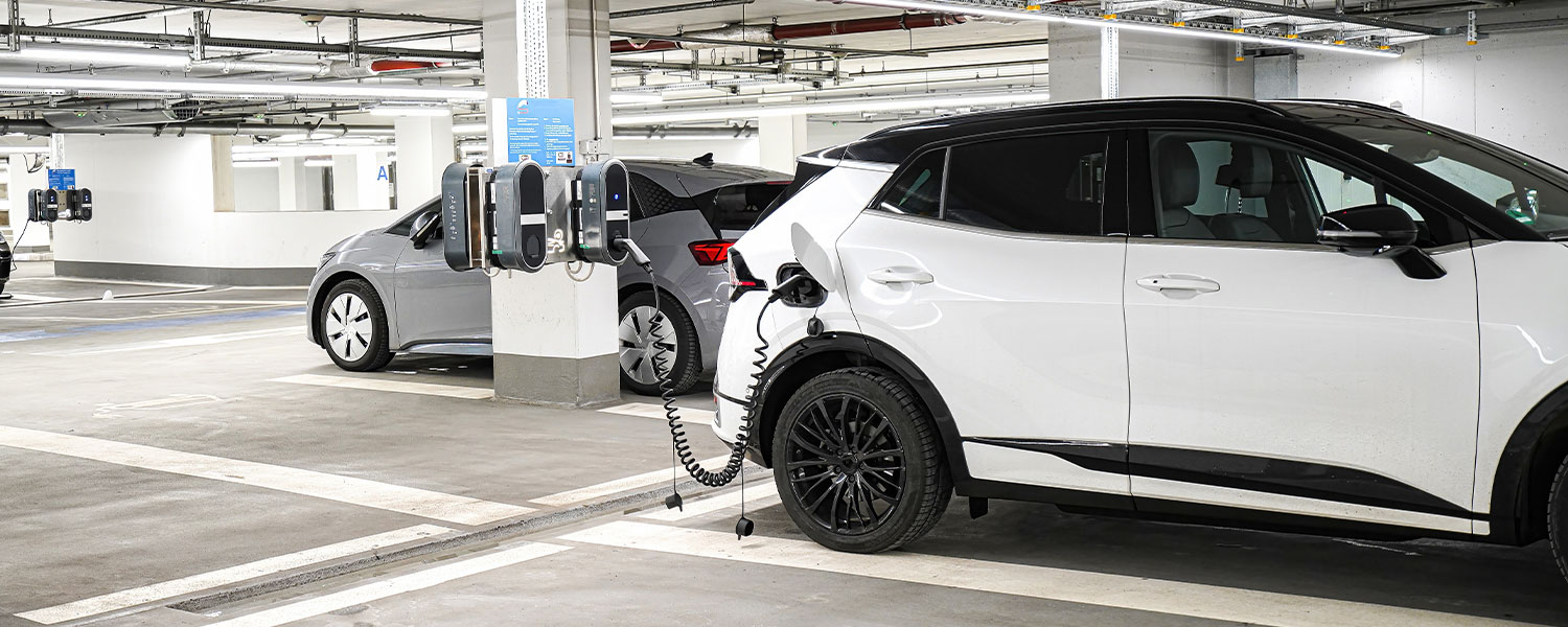 Vehículo eléctrico recargando en estación urbana en Valencia, asociado a deducciones fiscales 2025