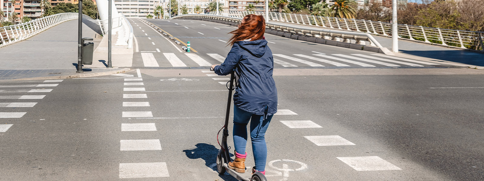 Empleado aparcando un patinete eléctrico fuera de un edificio de oficinas